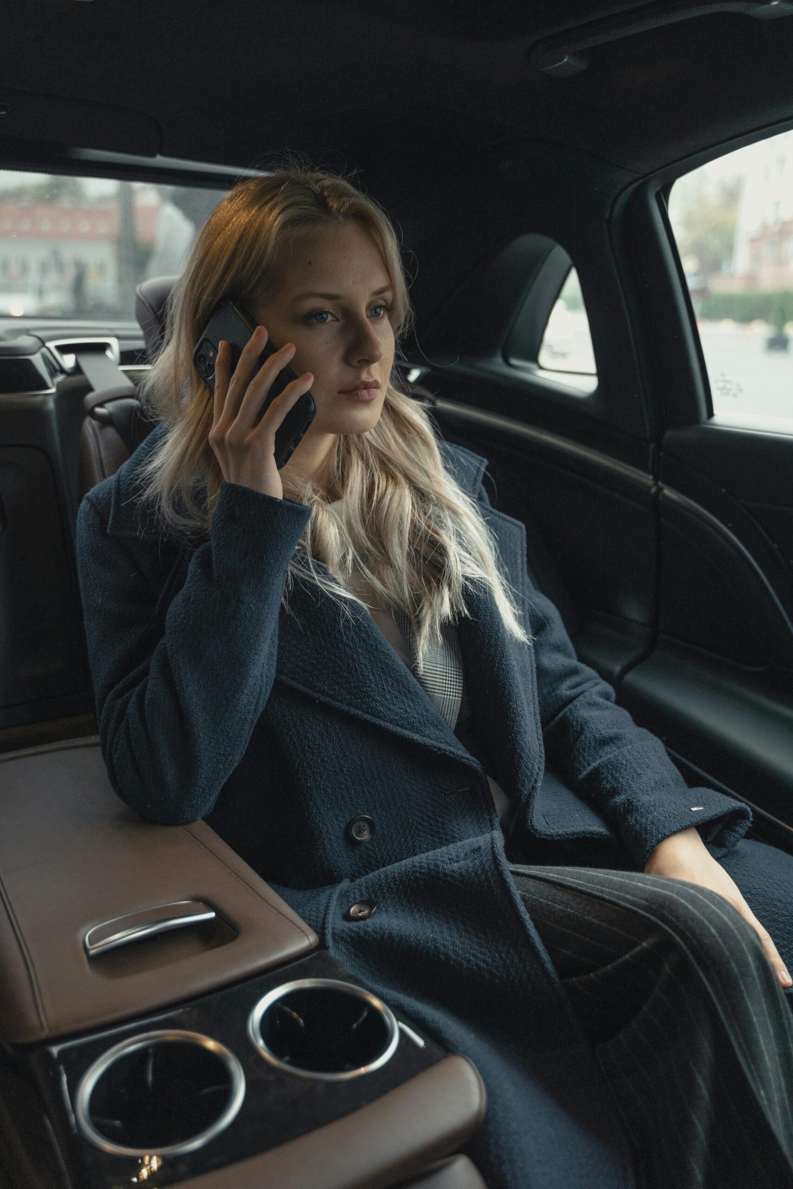 A professional woman talking on her mobile phone while sitting in a luxurious car, portraying success and elegance.